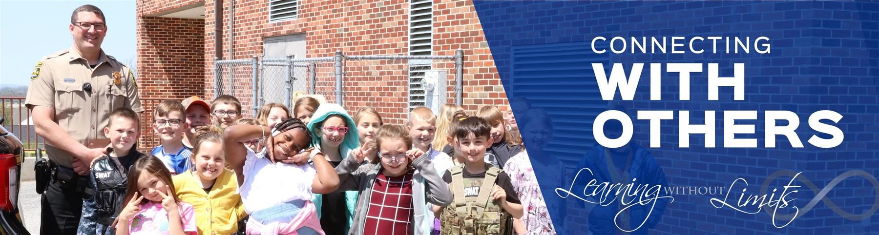 Elementary class group with school resource office. Connecting with others. Learning Without Limits.